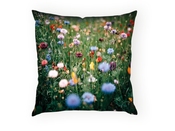 Bunte Wildblumenwiese mit roten, blauen und violetten Blüten in voller Blüte auf einem Kuschelkissen.